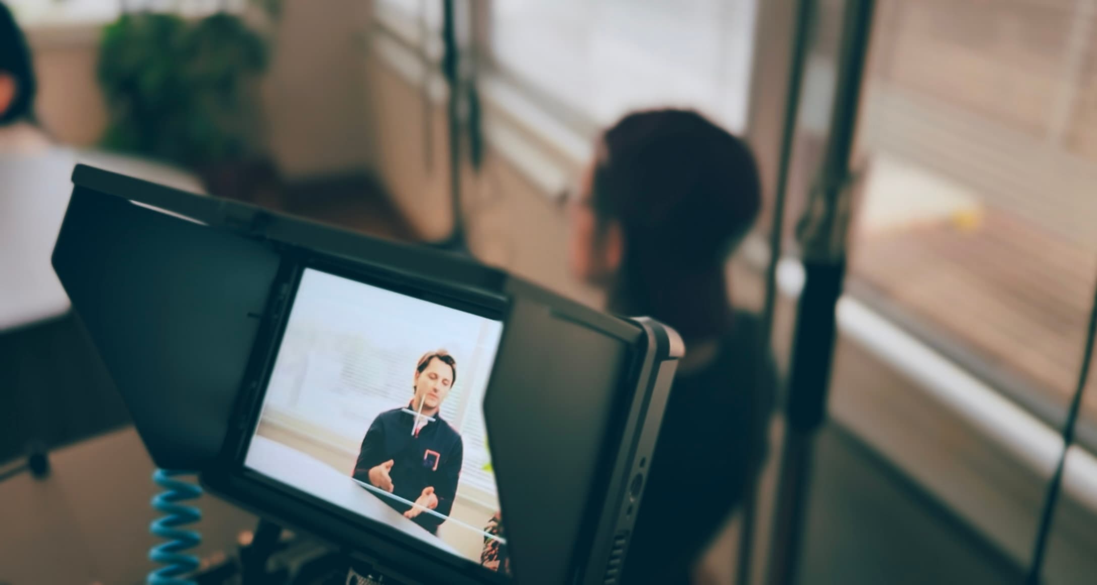 A production monitor showing the live interview feed during a Boda Studios shoot, with the on-camera subject blurred in the background