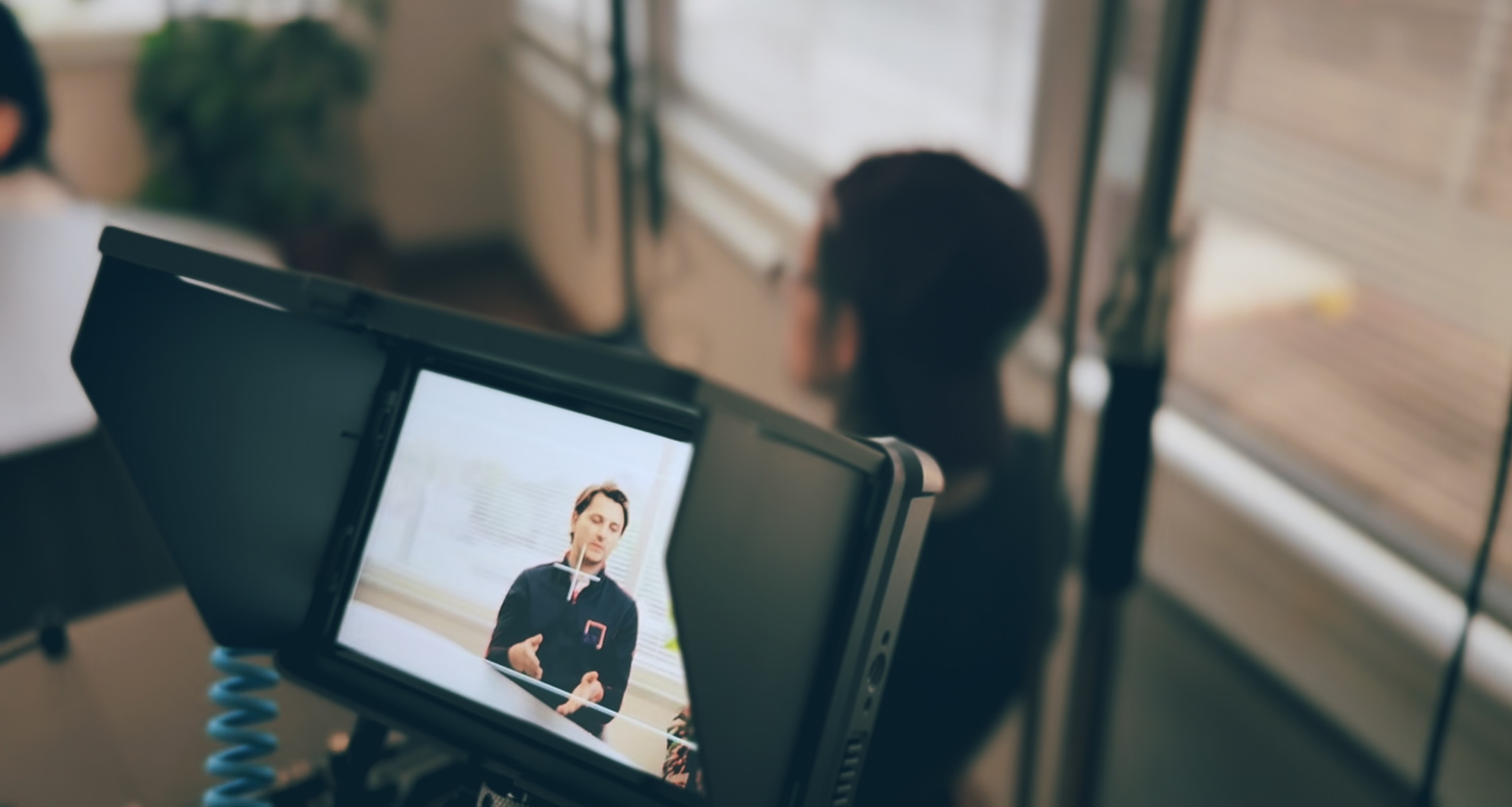 A production monitor showing the live interview feed during a Boda Studios shoot, with the on-camera subject blurred in the background