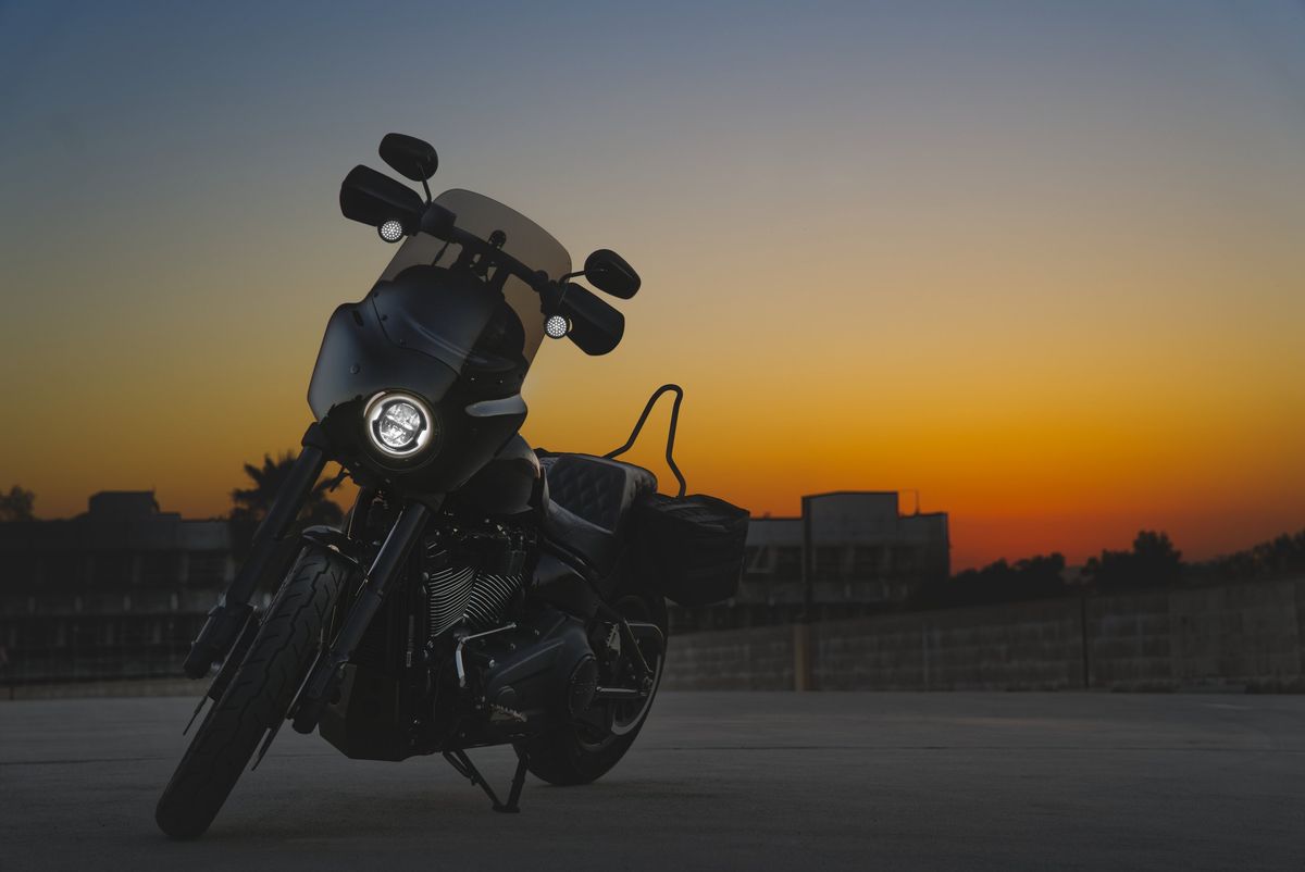 Motorcycle silhouetted against an orange sunset, photographed by Boda Studios