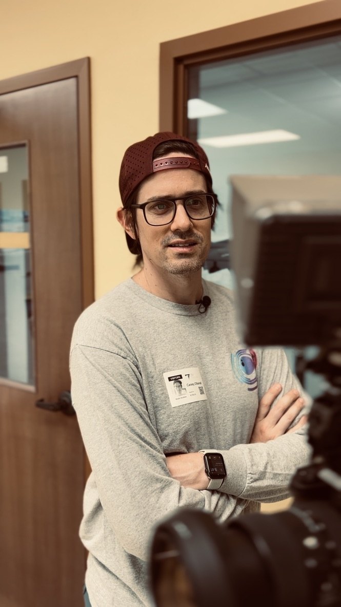 Casey O'Farrell on set, arms crossed beside a cinema camera